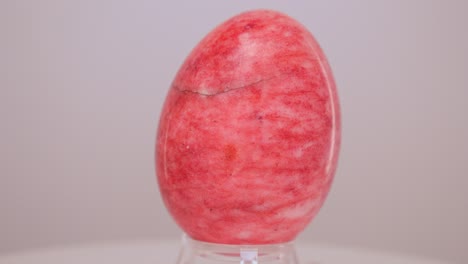 red marble egg rotating slowly on a turntable in front of a white background