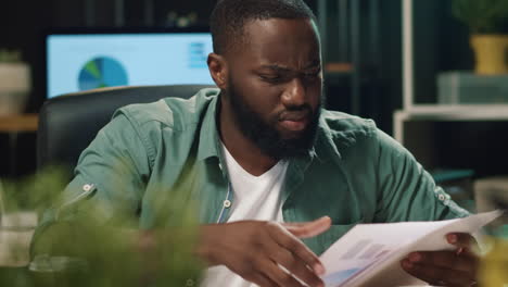 Closeup disappointed afro business man looking papers in hipster office.