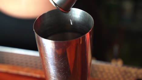 bartender pours alcohol into a jigger mixer close up