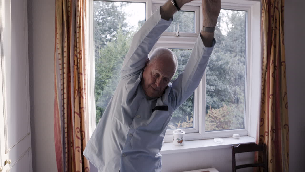 Elderly man stretching in his bedroom