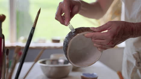 woman decorating a ceramic bowl