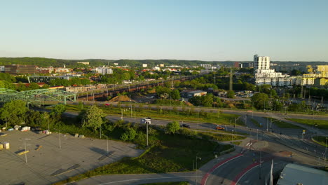 Toma-Aérea-Ascendente-Del-Tráfico-En-La-Carretera-Cerca-De-La-Estación-De-Tren-Durante-La-Puesta-De-Sol-En-Gdansk,-Polonia