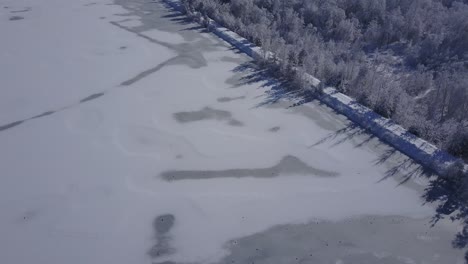 4k aerial video view of alpine snowy valley forest road and frozen river in peak of winter overflight - drone collection stock video