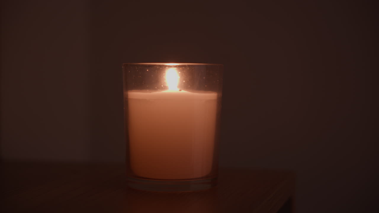 Medium shot of a person that lights the candle in a dark room