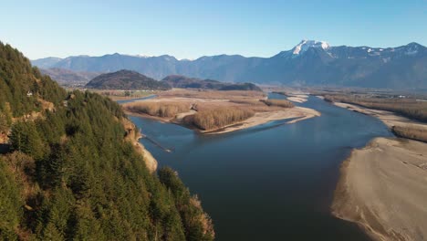 Cinematic-Scene-of-the-Fraser-River-Valley-in-the-Lower-Mainland-in-BC,-Canada,-on-a-sunny-day-in-autumn,-snow-capped-mountains,-blue-sky