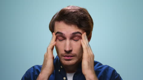 portrait of tired man having headache. stressed man face on blue background