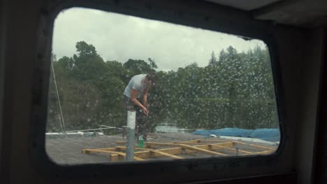 ver a través de la ventana del barco lluvioso joven trabajando