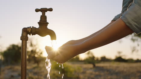 Frauenhände-Fangen-Wasser-Unter-Leitungswasser-Auf-Durstiger-Bauer-Trinkt-Süßwasser,-Das-Bei-Sonnenuntergang-Aus-Dem-Wasserhahn-Fließt,-Spart-Wasserkonzept