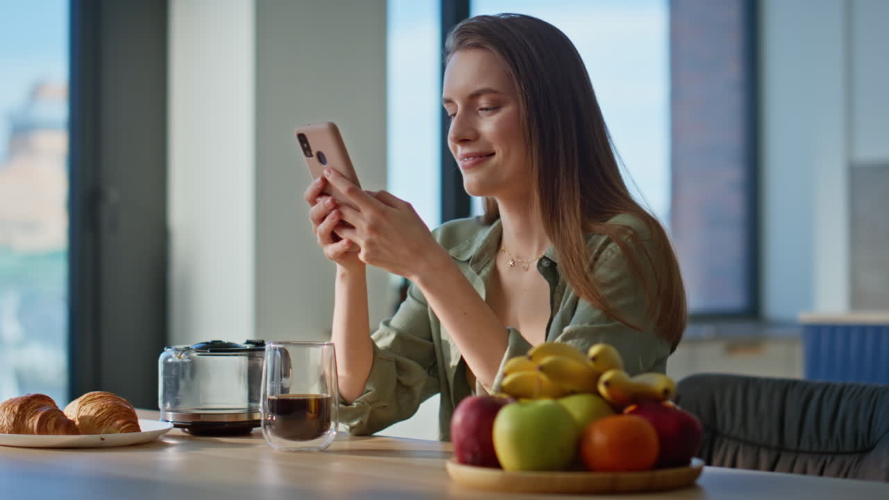 Happy woman sitting breakfast table looking smartphone with smile closeup