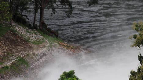 water raging from a dam at kaeng krachan reservoir in thailand with thick mist rising upward