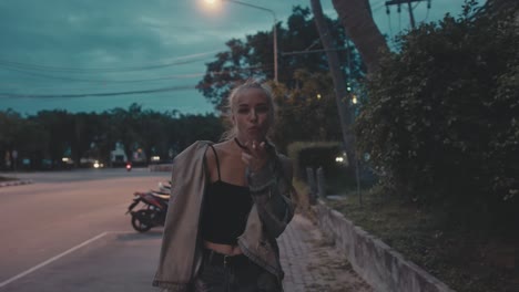 young woman smoking on city street at dusk