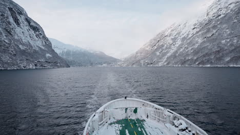 slow motion pov of a winter ferry boat ride in geirangerfjord to geiranger, norway, with snowy mountains and captivating fjord views