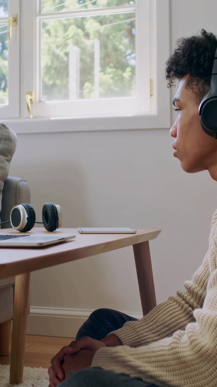 Vertical video: Reaching teen in ribbed top after blink placing headphones by window to hear tablet