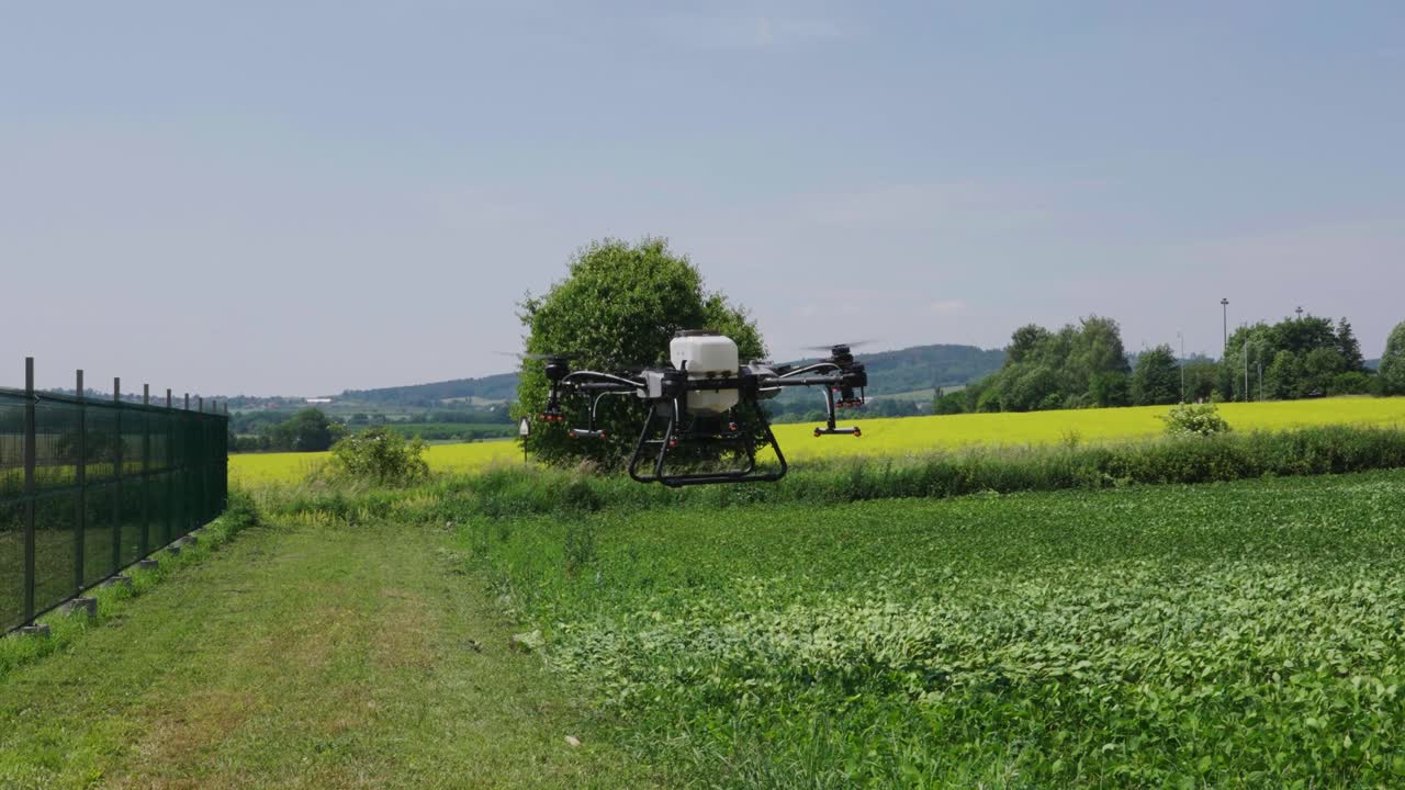 물 크와 스프레이 시스템이 있는 농업용 드론이 초록색 농경지 위에 떠 있습니다.