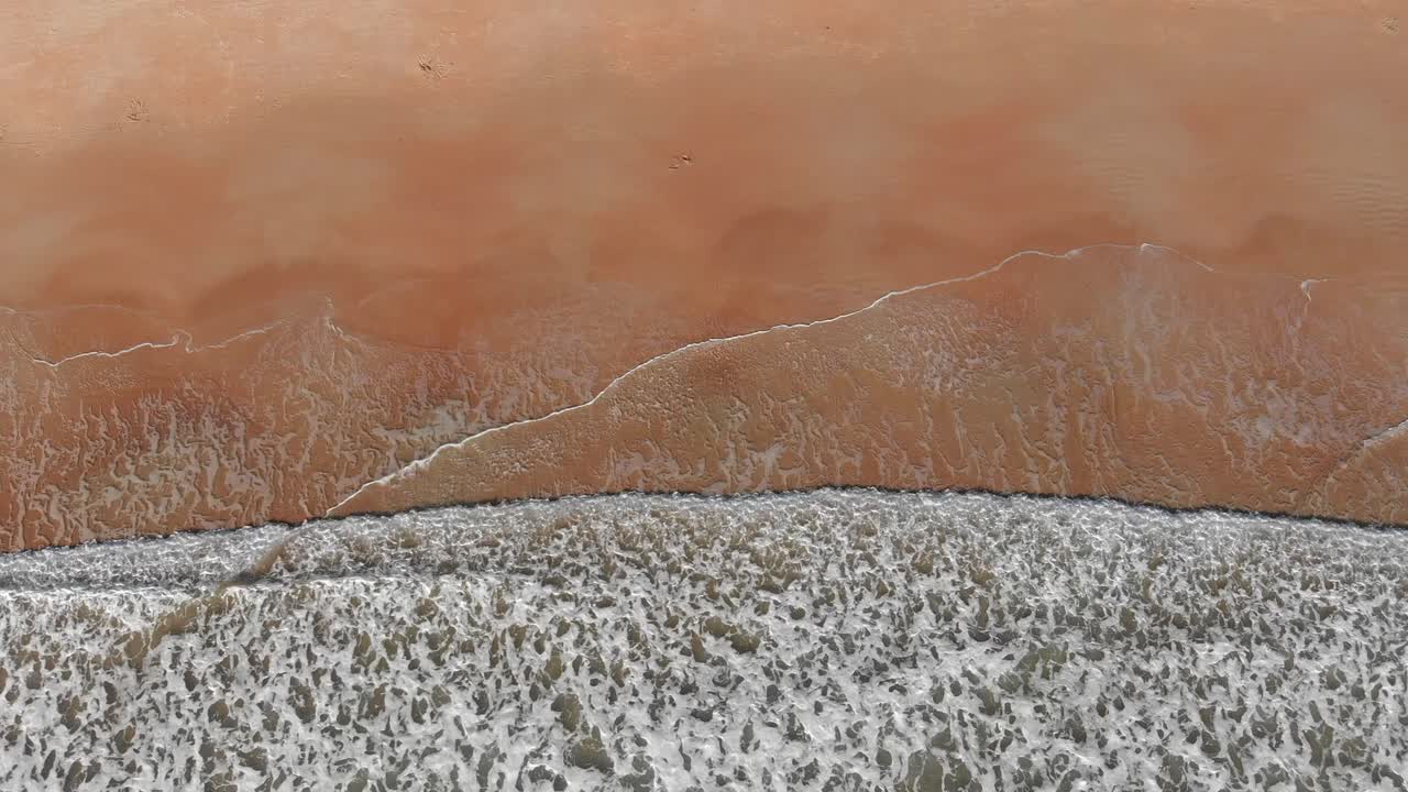 저지, 채널 제도의 모래 해변에서 파도가 부서지는 파도의 공중 샷