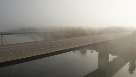 aerial view from drone flying beside empty highway bridge in early morning fog