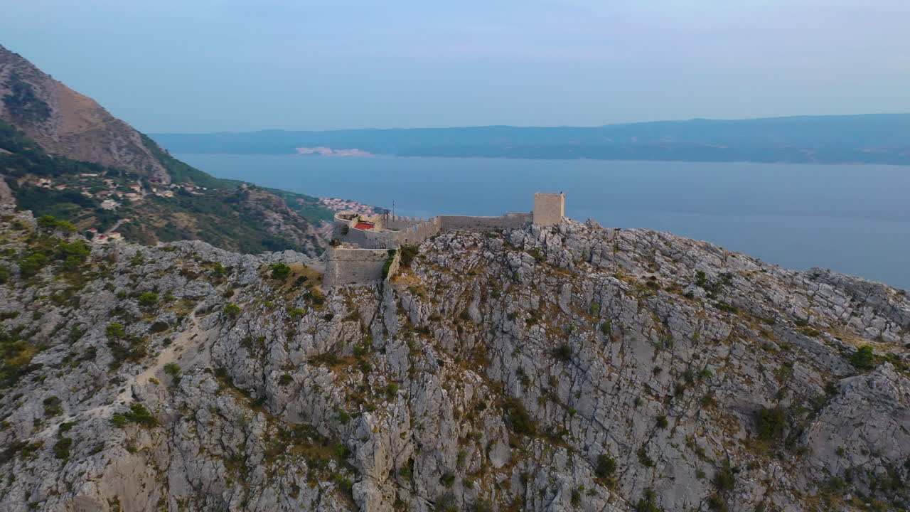 antena: fortaleza de starigrad en la cima del acantilado adriático, omis croatia, toma de arco al atardecer