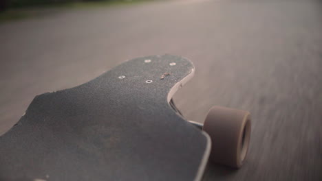 low angle perspective of longboard as it rides down the road at golden hour