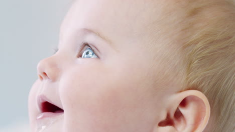 close up of happy baby boy sitting on parents bed