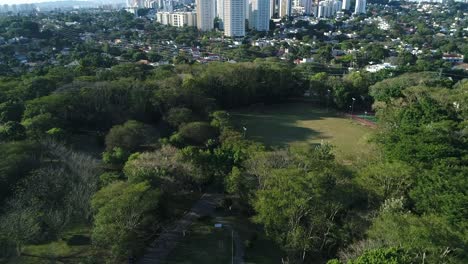 drone flying in public park with lots of nature and beautiful trees towards soccer field, sports, health, leisure, in 4k resolution