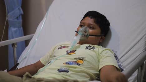 Asia-boy-sleeping-on-bed-while-making-inhalation-with-nebulizer-mask-at-the-hospital