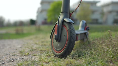 close up of electric scooter wheel parked over grass, circle pan, soft focus