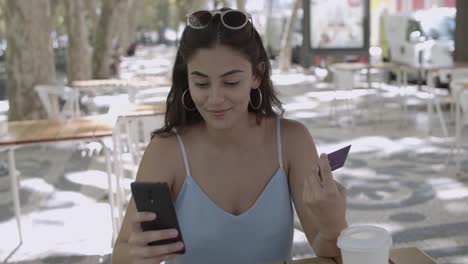 pretty woman haciendo el pago con tarjeta de plástico a través de smartphone