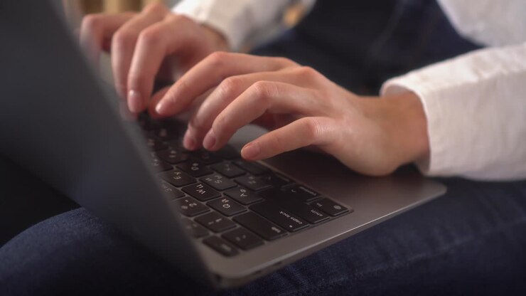 Nahaufnahme einer arbeitenden Frau, die zu Hause am Laptop tippt