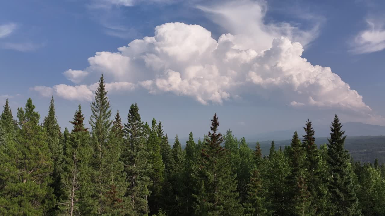 Stigende dronevideo afslører et fjernt tordenvejr over forbjergene i Alberta, Canada.