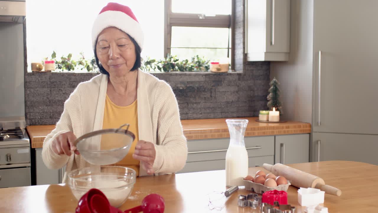 Elderly woman in Santa hat baking Christmas cookies in cozy kitchen
