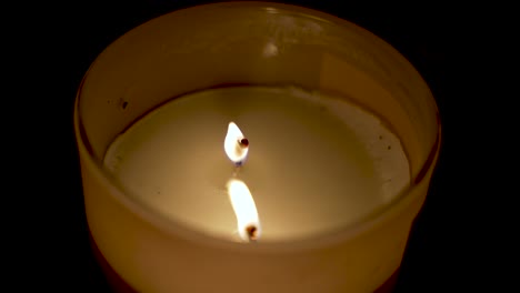 primer plano de la llama ardiente de cera perfumada en fondo oscuro