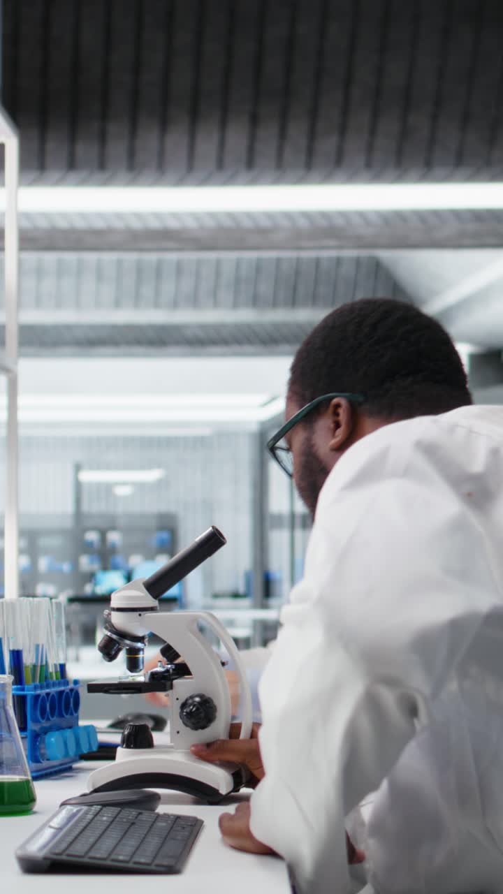 Vertical video Senior researcher records observations from coworkers using microscope