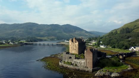 Eilean-Donan-Castle-in-the-highlands-of-Scotland,-UK-_-drone-shot-sunset-with-beautiful-lake,-orbiting-close-up