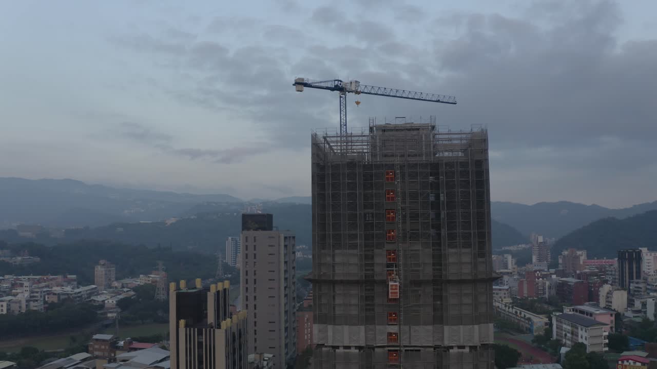 una toma de un avión no tripulado de un edificio en construcción en taipei al anochecer donde se puede ver un ascensor subiendo
