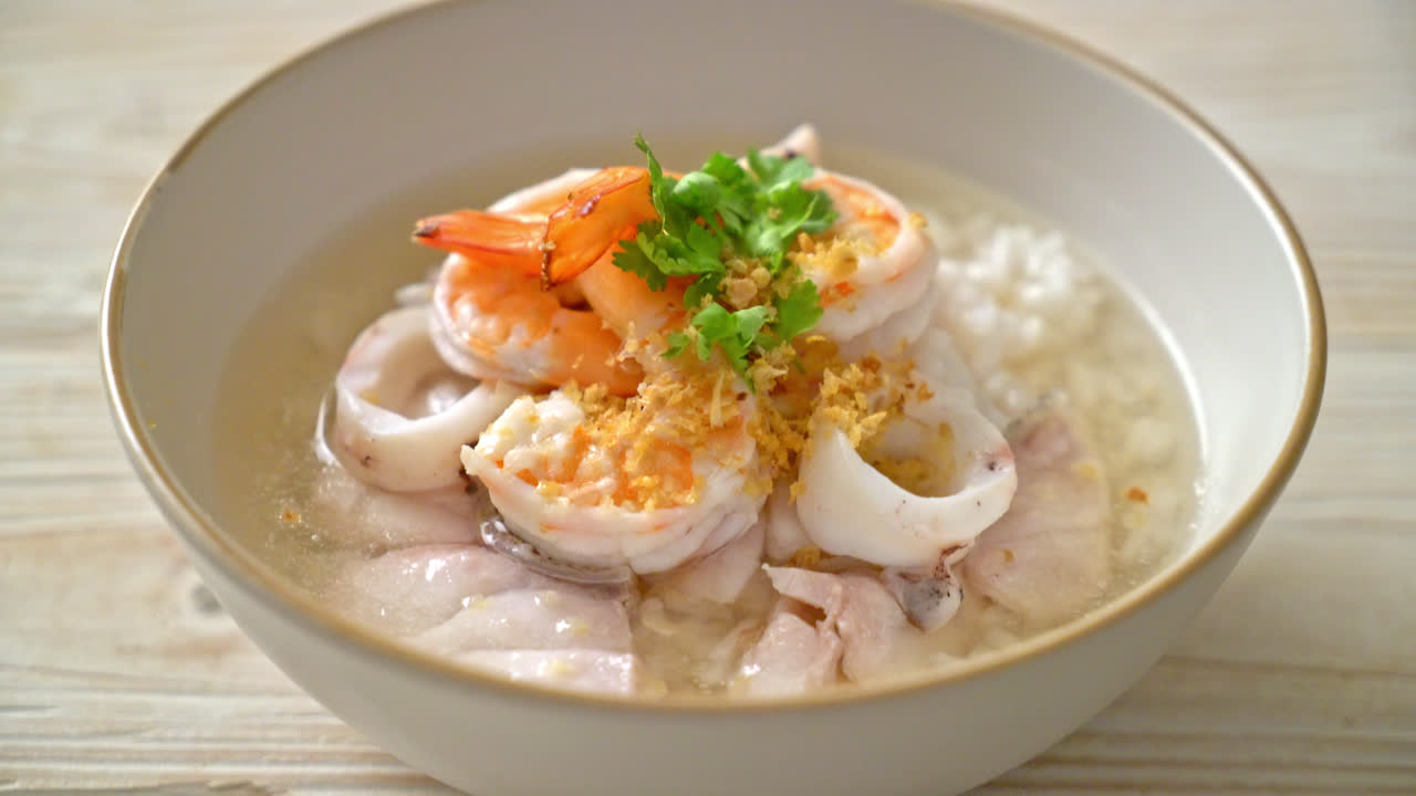 해물(새우, 오징어, 생선)을 곁들인 죽 또는 삶은 쌀국수 그릇