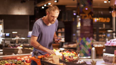 Caucasian-young-man-checking-product-list-on-smartphone-in-a-supermarket