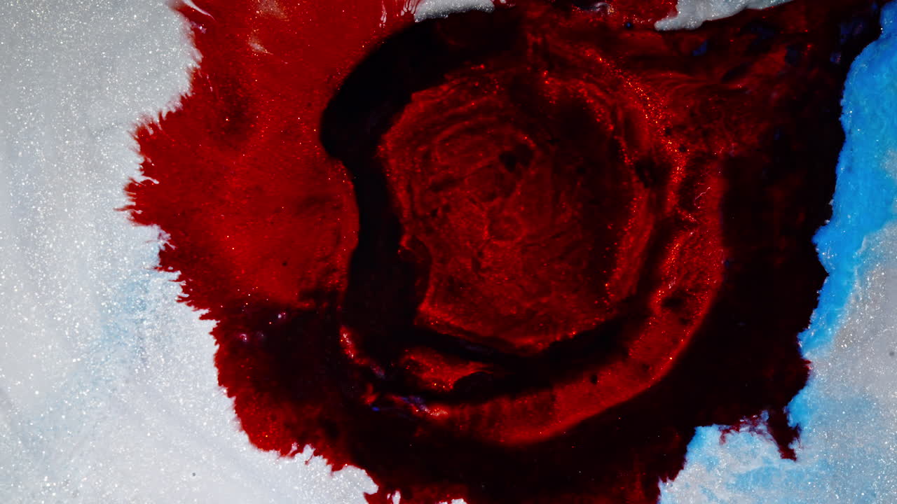 Swirling red ink on a white background, creating abstract shapes and textures