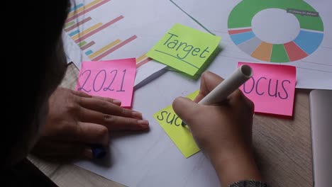 primer plano de la mano de una mujer que escribe la palabra éxito en una nota adhesiva amarilla con rotulador negro