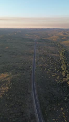 aerial reveal of a solitary road stretching through the outback at golden hour, captured in the northern territory.