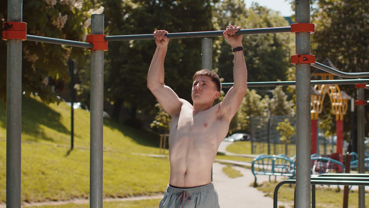 Athletic caucasian topless muscular man doing pull ups exercises on horizontal bar pumping up back