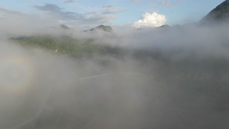 drone flies through the cloud to reveal a bridge along below green mountain range