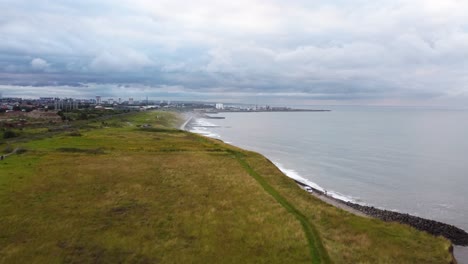 Aerial-drone-shot-flying-over-the-cliffs-of-the-north-east-English-Coast,-look-over-the-City-of-Sunderland-on-a-cloudy-day
