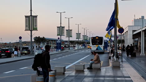 people waiting at an airport bus stop