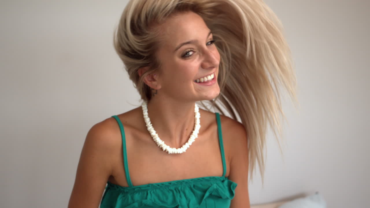 매력적인 금발이 머리카락을 던지고 있습니다.