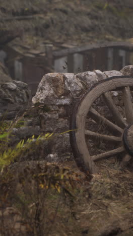 ancient wooden wheel by stone wall in foggy ruins