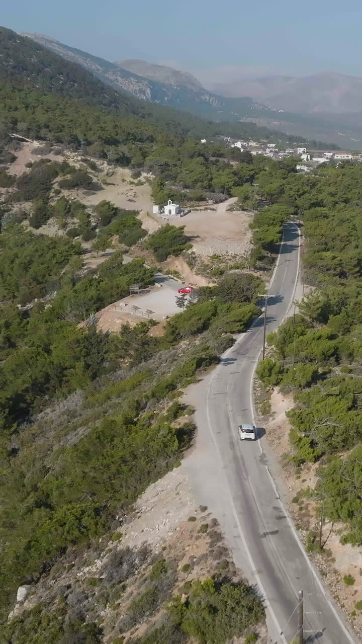 Vertical drone shot following a car driving in the mountains of west Rhodes