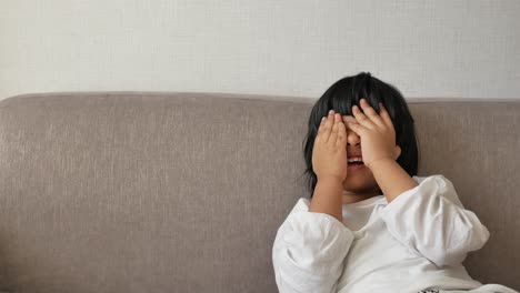 a child hiding her face on a couch