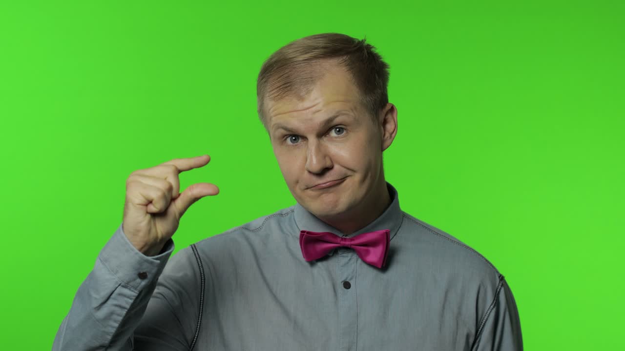 카메라를 바라보는 남자가 작은 크기, 낮은 규모에 대해 회의적으로 느지는 작은 몸짓을 보여줍니다.