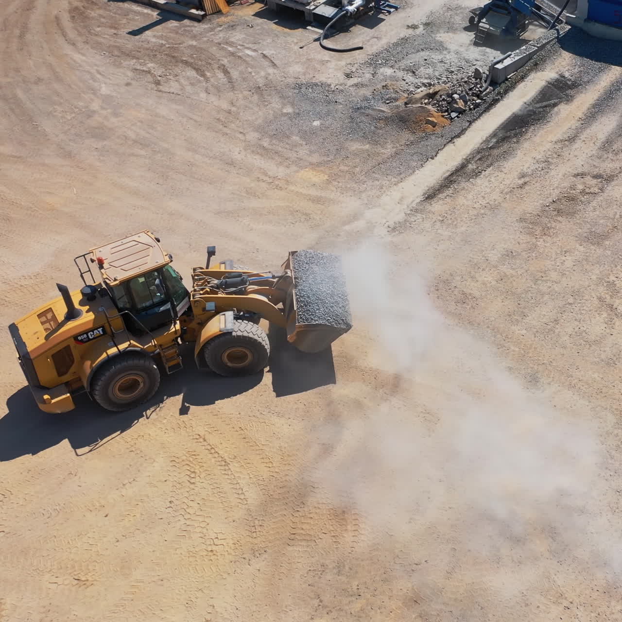 Asphalt plant with running bulldozer. The plant serves the needs of road construction. Industrial machine is loading rubbles. Aerial view.