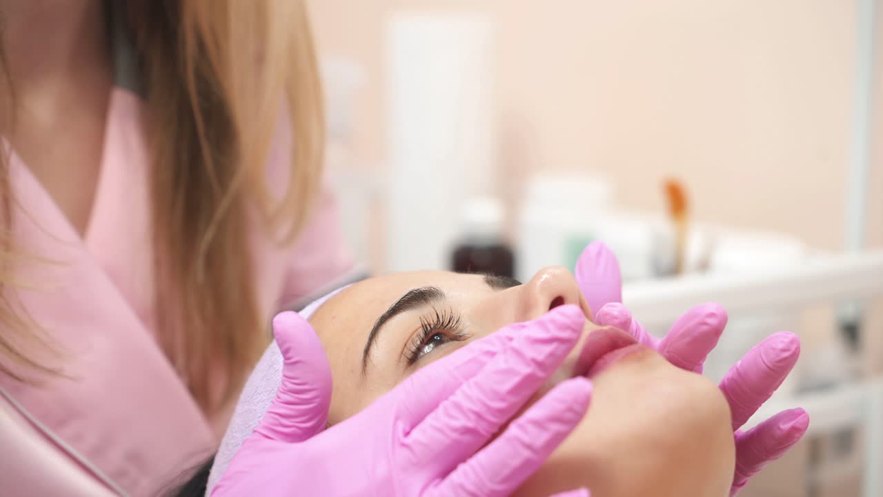 Girl relaxing in spa salon. Beautician applies the mask to the face of beautiful young woman in the spa salon